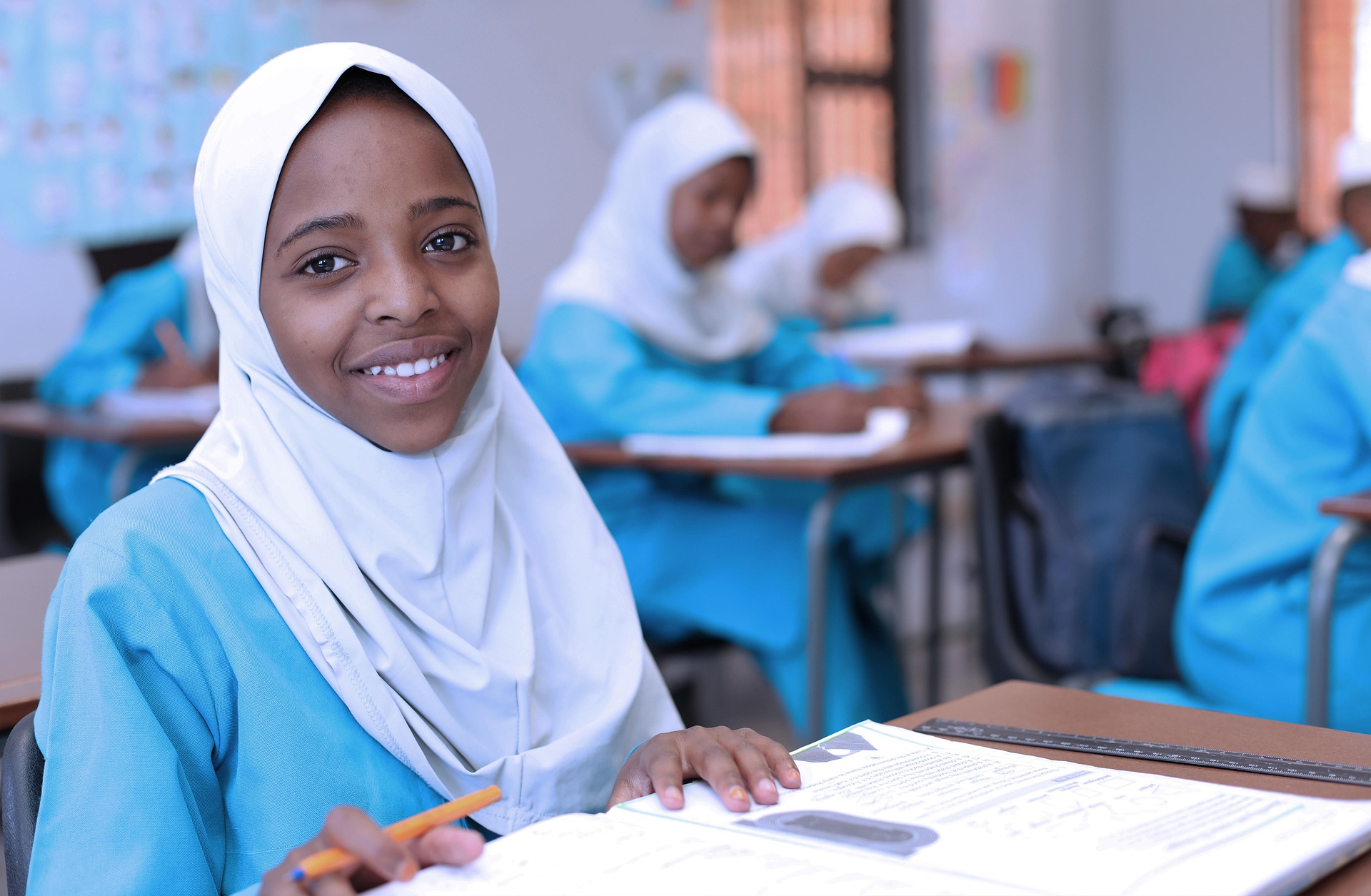 Jeune élève souriante en classe, utilisée comme visuel principal de la homepage KNIPO